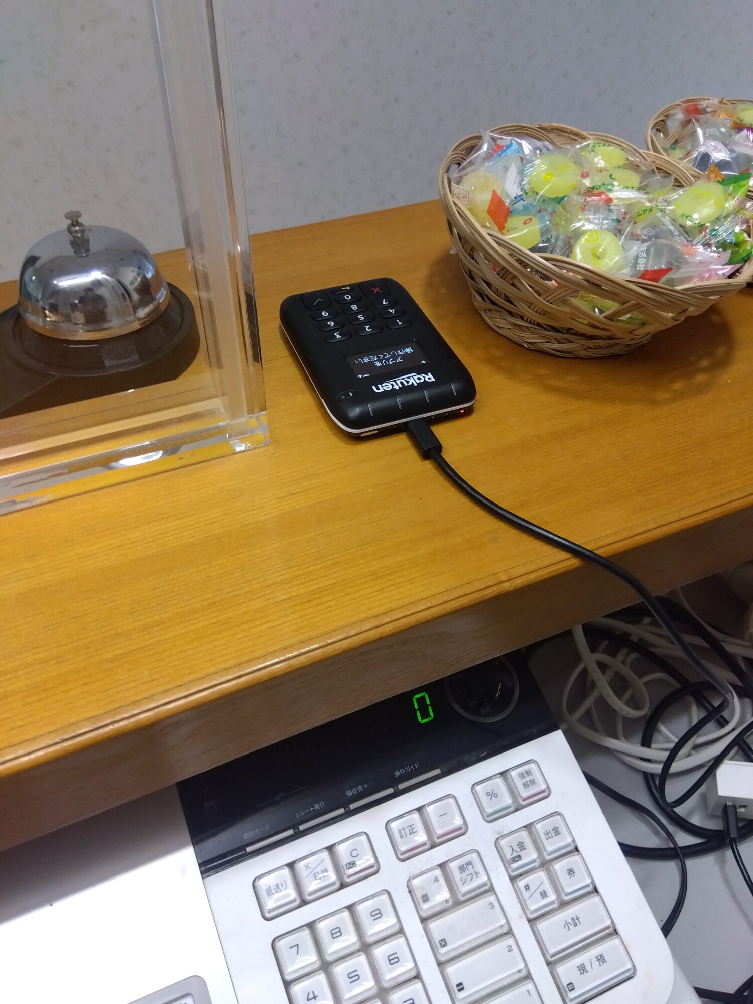 おおの接骨院の受付カウンターに置かれた楽天ペイカードリーダーと呼び鈴