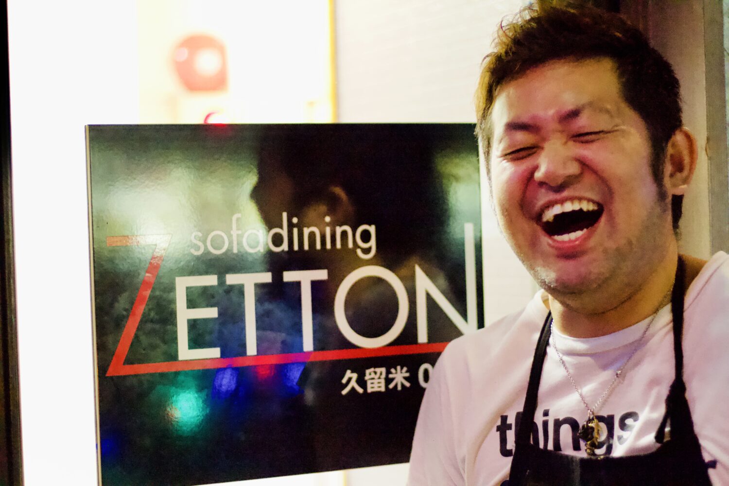 福岡県久留米市のダイニングバーZETTONの看板前に立つ店長の藤丸さん