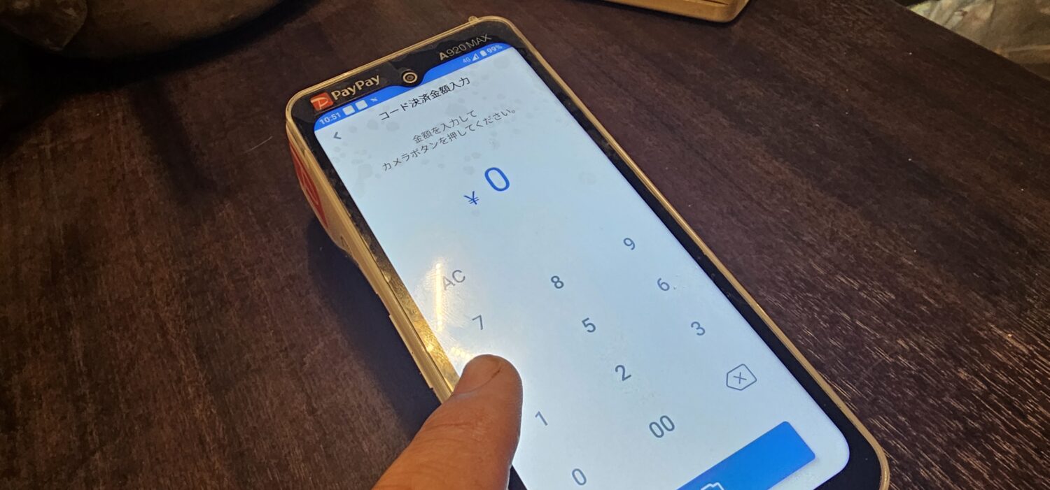 PayCAS Mobileのコード決済金額入力画面と数字キーを操作する指