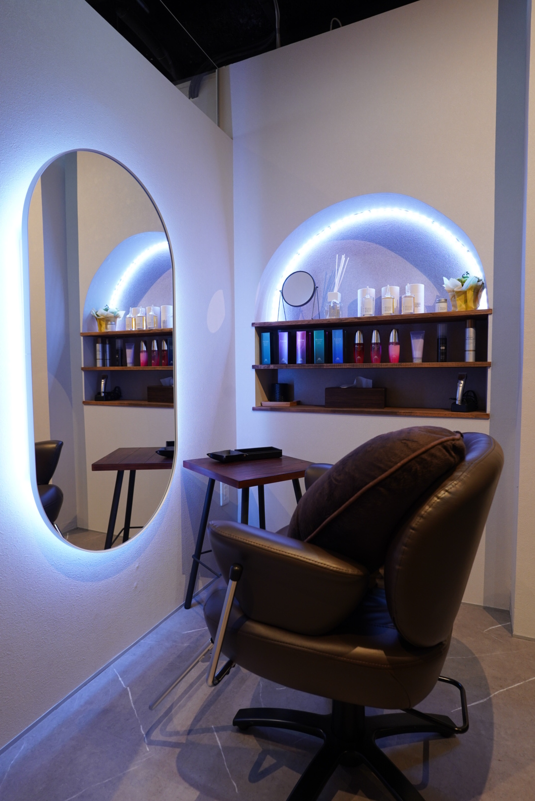 glanlichtの施術席と照明付きの鏡、ヘアケア商品が並ぶ棚