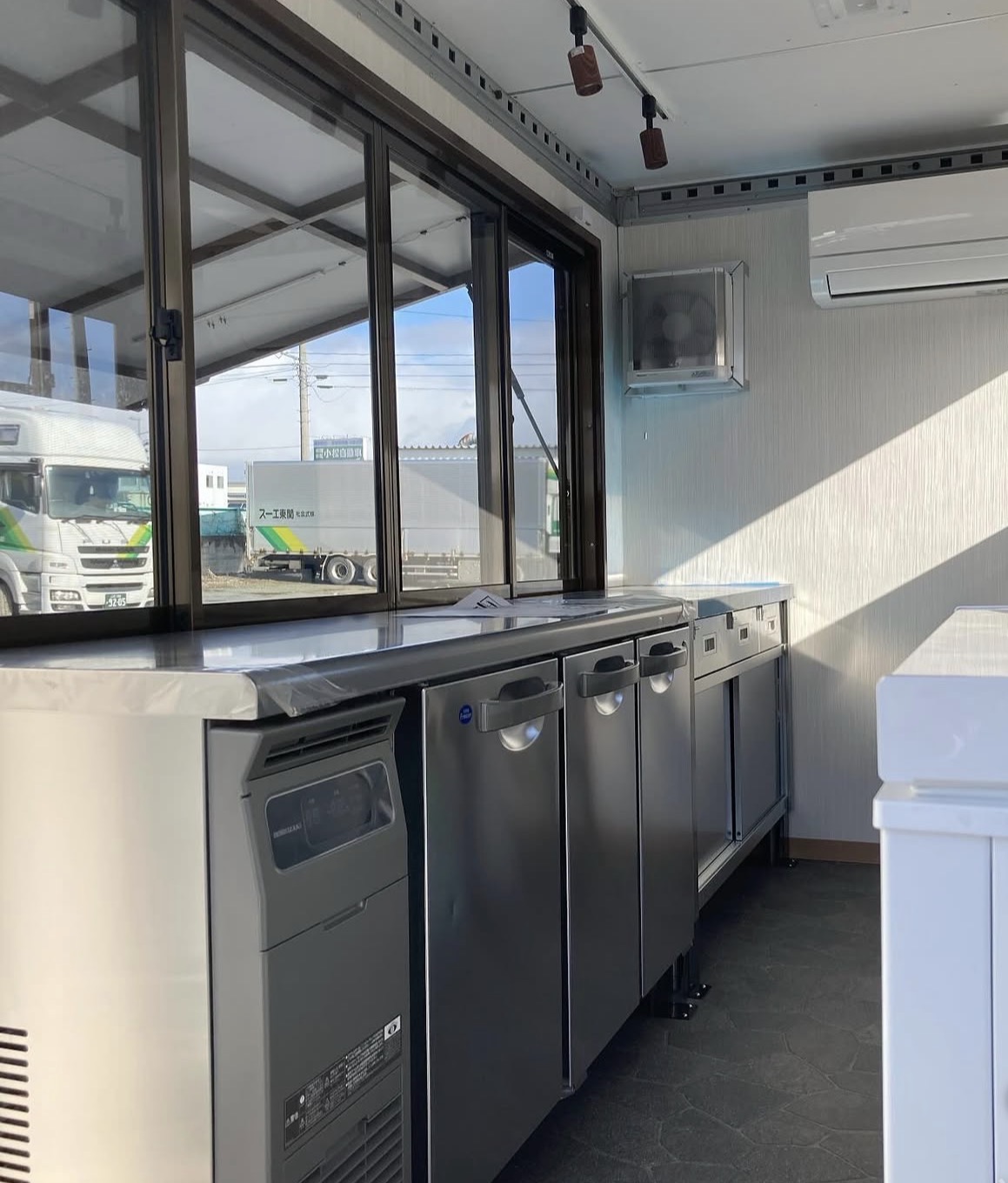 受け渡し窓とステンレス製の厨房設備が並ぶ3KITCHENのキッチンカー車内