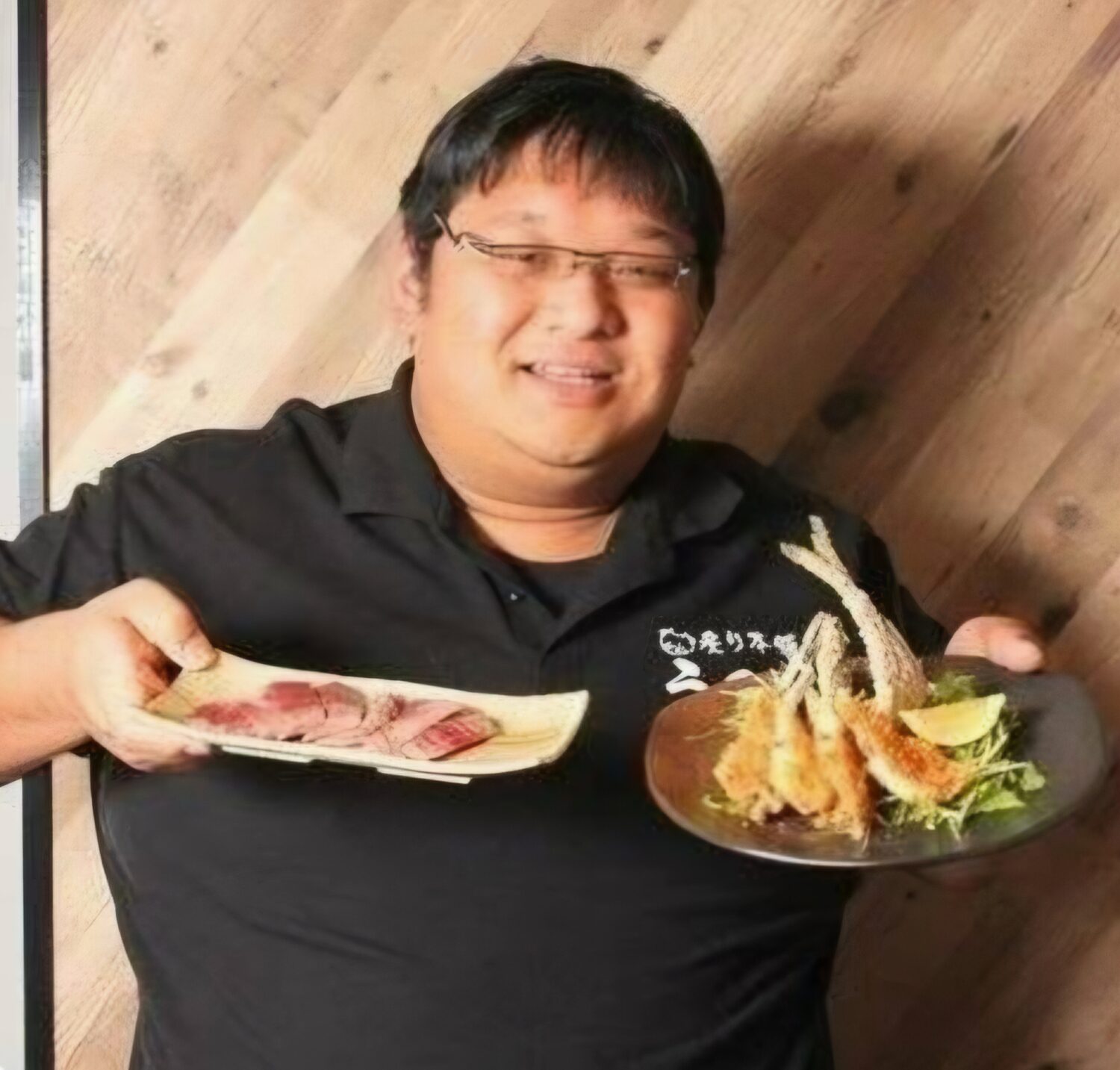 料理の皿を持つあぶり居酒屋うのっちの代表・宇野喜厚様