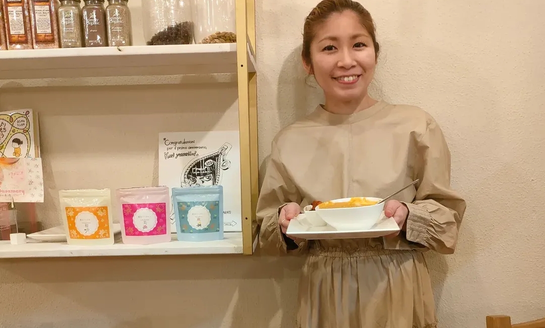 薬膳スパイスカレー専門店カリーユズリハの店内でカレーを持つ人物